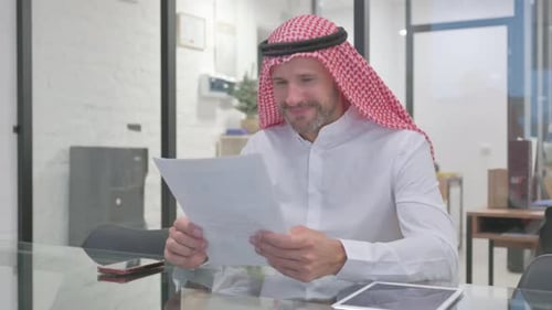 Man in Traditional Headdress Reads a Document