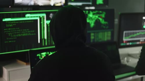Hooded Hackers Working at Computers in Dark Room