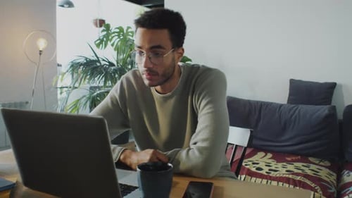 Young Man Video Calling on Laptop in Home Office