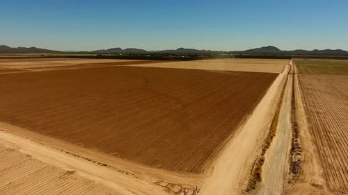 Rotating drone shot of farm field with mountains