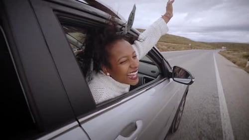 Happy Woman Leaning Out Car Window on Road Trip