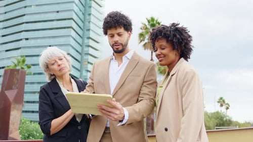 Business Team Collaborates on Tablet Outside Office Building