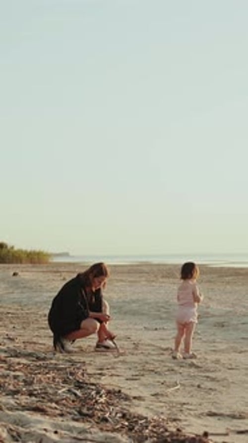 Vertical Video A Mother Joyfully Shares a Moment with Her Child on a Beach at Sunset Creating