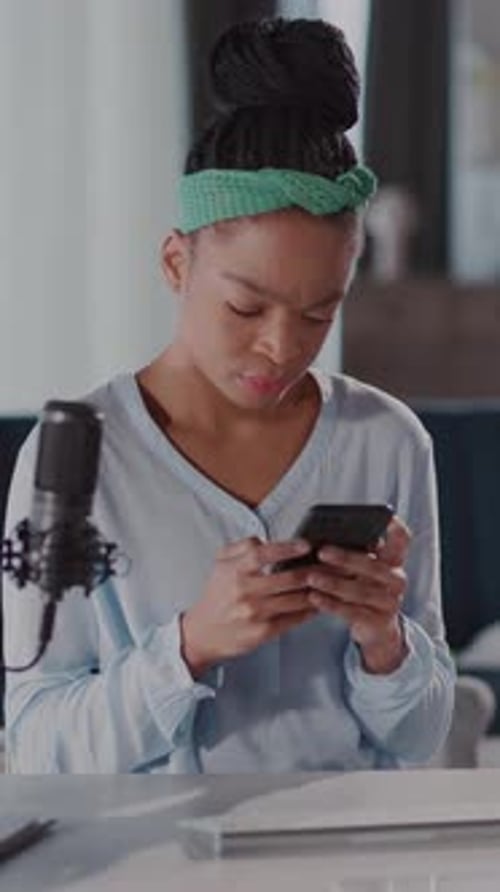 A Woman with a Green Headband Engages with Her Cellphone Indoors