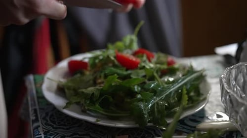 Hands Taking Care in Preparing a Wholesome Green Salad with Fresh Tomatoes in the Kitchen