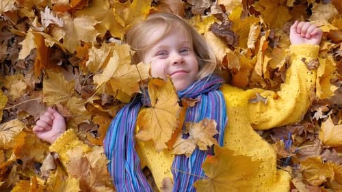Happy Girl Lying in Golden Autumn Leaves