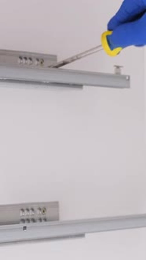 Gloved Hand Adjusts Furniture Hardware with Screwdriver