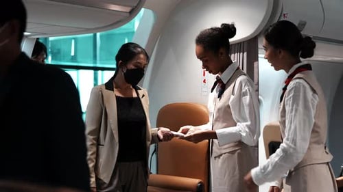 Two beautiful young female flight attendants in uniform stand at the airplane entrance service