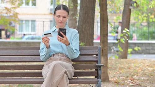 Woman Uses Phone, Credit Card on Park Bench