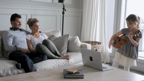 Loving Family Watching Child Playing Ukulele at Home