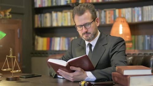 Middle Aged Lawyer Reading Book in Office