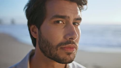 Sexy Bearded Man Looking Camera with Daring Smile Posing on Ocean Coast Close Up