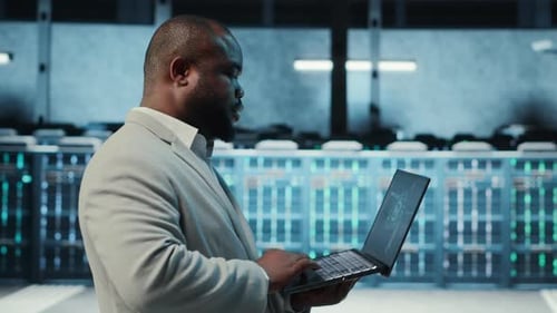 Manager Overseeing Server Room Walking with Laptop Troubleshooting Hardware