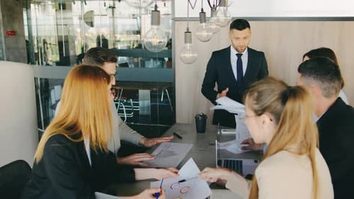 Engaged in a Contemporary Office Setting During a Business Meeting with Colleagues Focusing on