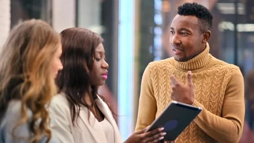 Multiracial group of workers in an office discussing business affairs using a tablet. Slow motion