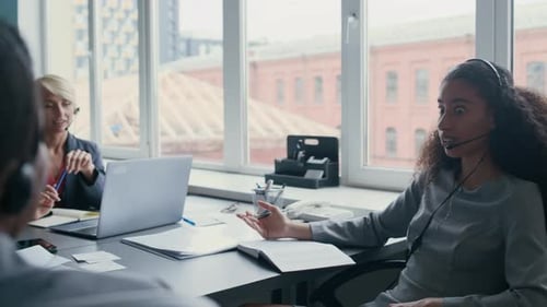 Team Members Communicate Wearing Headsets in an Office