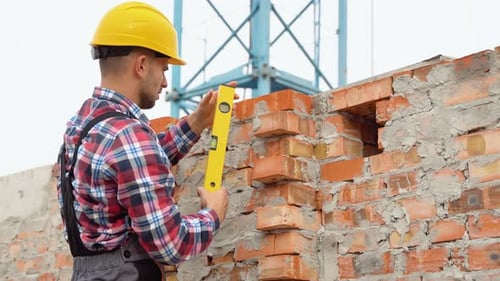 Man Leveling Brick Wall at Construction Site
