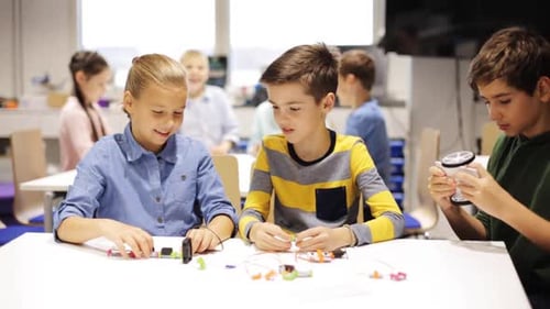 Smiling kids learning robotics and technology in a school science lesson