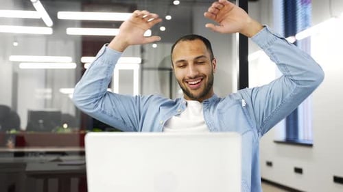 Young Adult Man Celebrating Success at Laptop