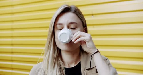 Young Woman Enjoying Coffee on Street