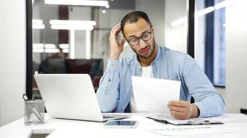 человек в растерянности смотрит на финансовые документы