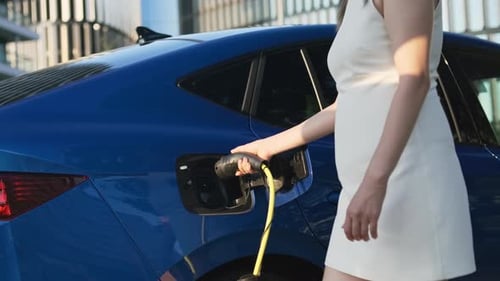 Businesswoman Connects Electric Car Charger at Outdoor Station