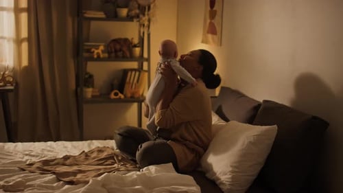 Glückliche afroamerikanische Mutter, die ihren kleinen Sohn im Schlafzimmer kuschelt und küsst