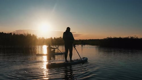 Stand Up Paddle Boarding or Standup Paddleboarding on Quiet Lake at Sunrise
