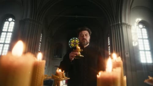 Priest Placing Candle on Altar Praying in Dim Lit Catholic Church