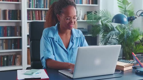 Young Optimistic African American Woman Secretary Typing Text on Laptop