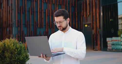 Man Working on Laptop Outside Office Building