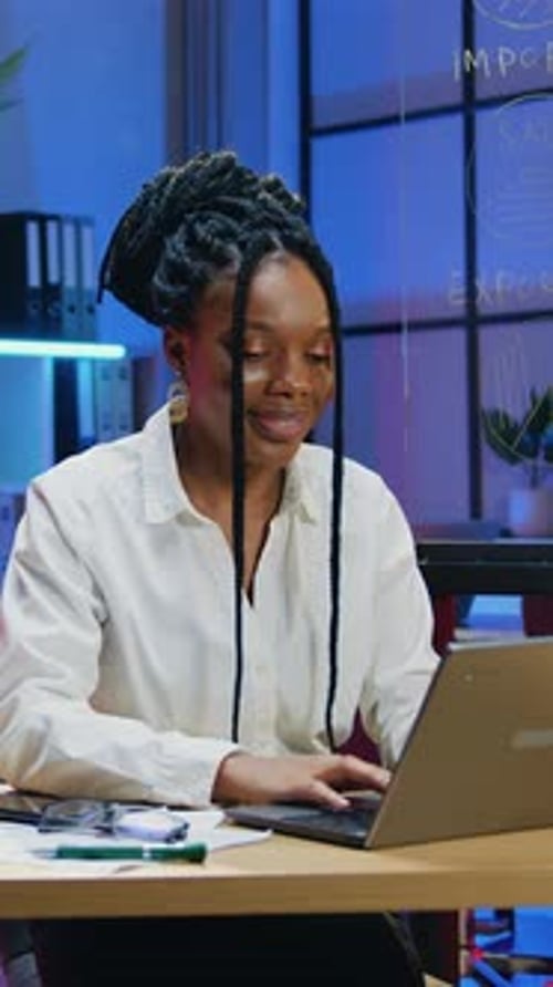 Attractive Woman Office Manager Overtime Working on Laptop on Night Lighted Workroom Background