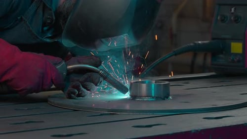 Welding sparks fly during work of welder at industrial plant