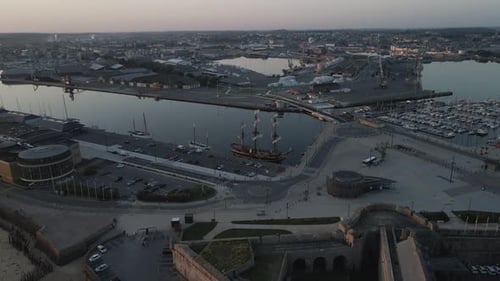 Old wooden ship moored on pier of Saint-Malo port area, Brittany in France. Aerial tilt down forward