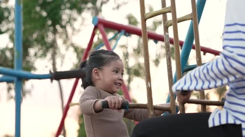 slow motion of cheerful child girl playing on double swing with her mother at outdoor playground