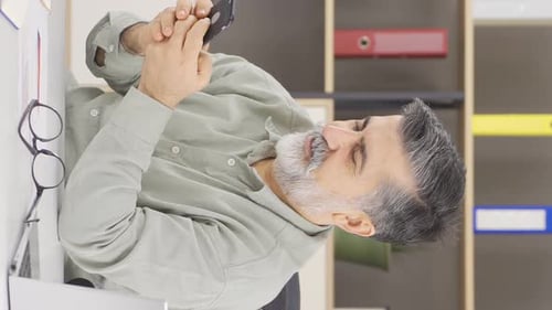 Vertical video of Happy office manager texting on phone.