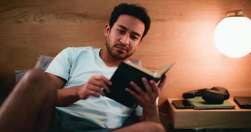 Relaxed Young Man Reading in Bed at Night