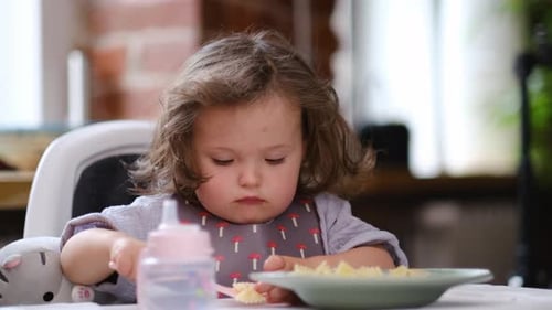 Cute Child Eating Pasta in a Highchair