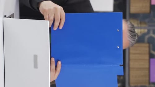 Vertical video of Cheerful businessman working on files.