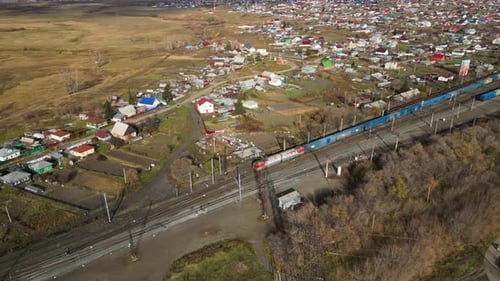 Der Güterzug fährt durch eine ländliche russische Landschaft und zeigt die weite Landschaft und