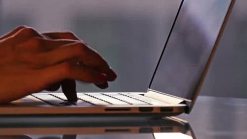 Woman Typing on Laptop Keyboard in Office