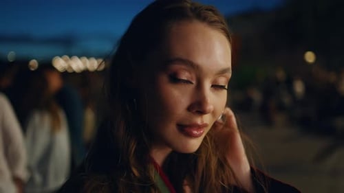 Retrato de mulher moderna festejando na cidade à noite procurando uma câmera na vida urbana