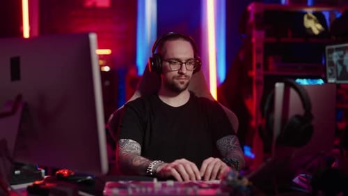 Man Typing at Computer Desk with Neon Lighting