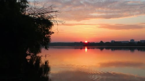 Sunrise on lake with clouds reflecting in water