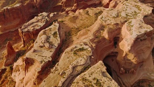 Unusual oddly-shaped red rocks of American canyons in Utah. Descending over a big rock