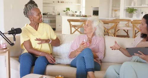 Diverses co-animatrices sur le canapé vérifiant les notes de la tablette après avoir laissé l'animatrice penchée et faisant des gestes, micro