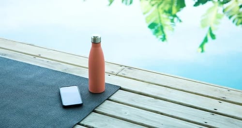 Yoga Mat, Water Bottle and Phone Beside Pool