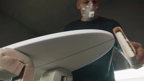 Surf factory. Adult male shaper creates the surfing board on the factory