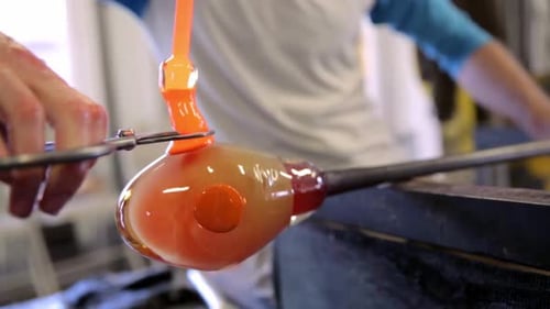 Glass Blower Shaping Molten Glass in Workshop