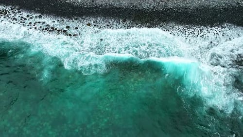 Waves Ocean Crashing Against a Ground of Black Rough Reef Rock Shallow Seashore The Rocks Eroded By